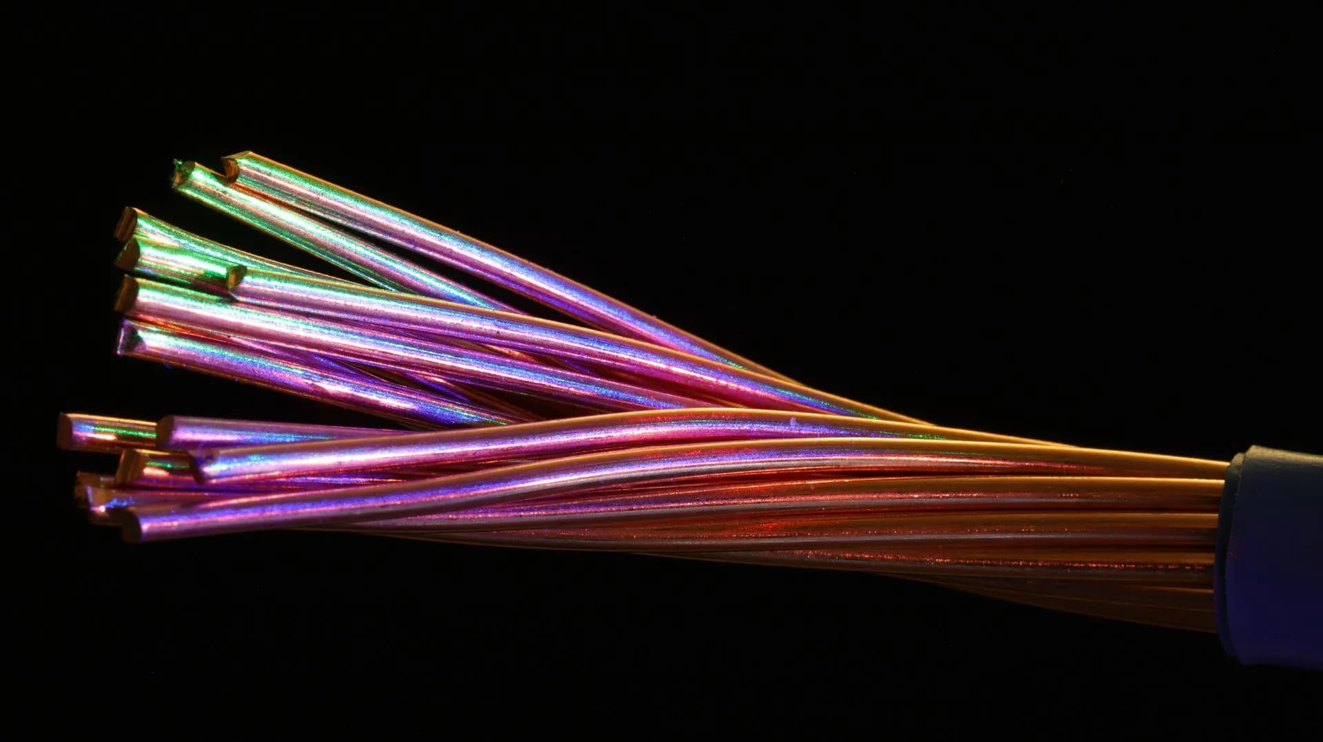Exposed copper wire strands with colorful reflections against a black background.